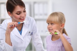 Il dentista e la bambina lavano i denti nel reparto di odontoiatria pediatrica