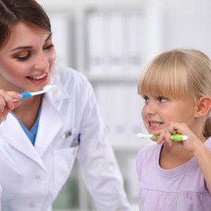 Il dentista e la bambina lavano i denti nel reparto di odontoiatria pediatrica