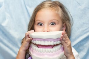 Una bambina che gioca con una dentiera