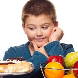 Un bambino indeciso tra dolci e frutta